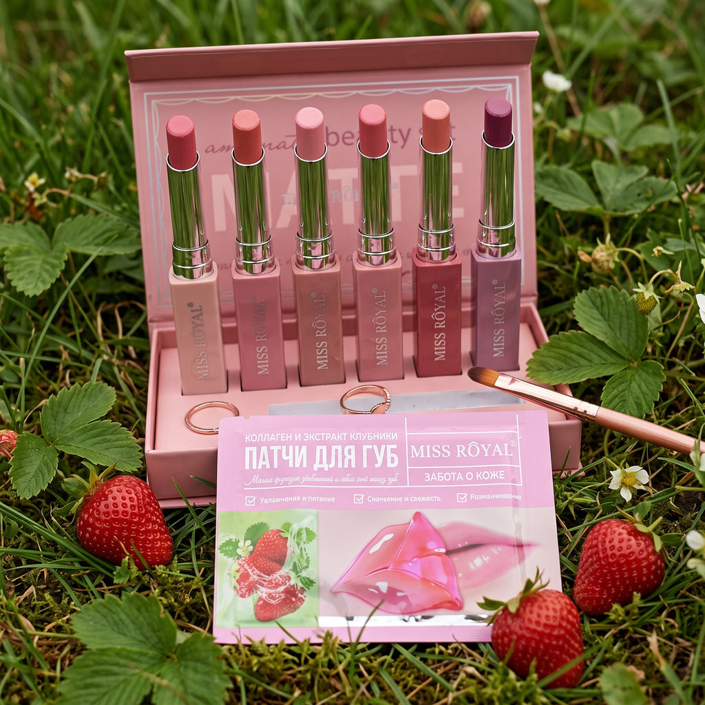 A pink display box holding six MISS ROYAL lip balm tubes in assorted pink shades, with a pink front card showing strawberry graphics and Russian text, set on artificial green grass against a white backdrop.