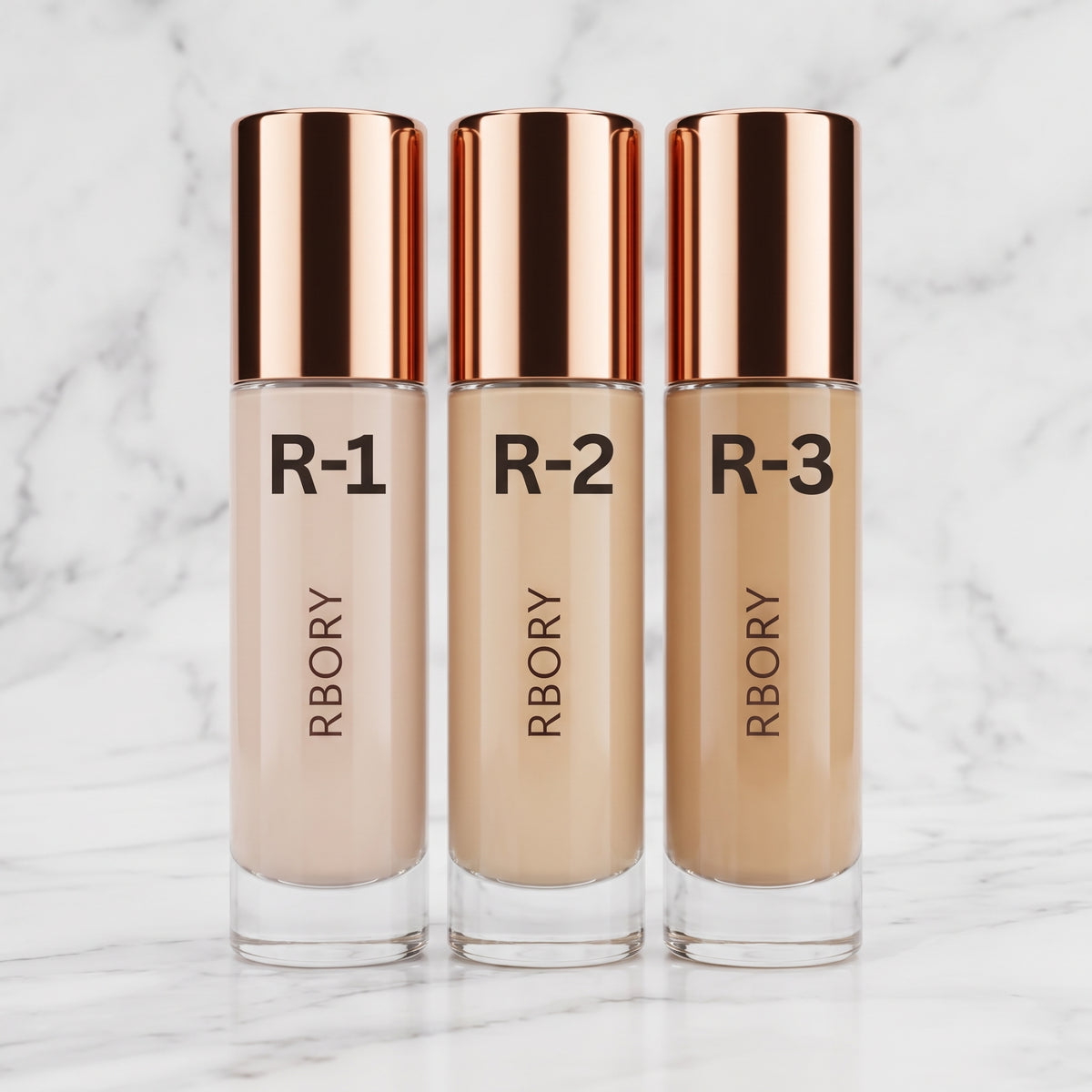 Three bottles of RBORY liquid foundation in shades R-1, R-2, and R-3, arranged side-by-side on a green grass background.