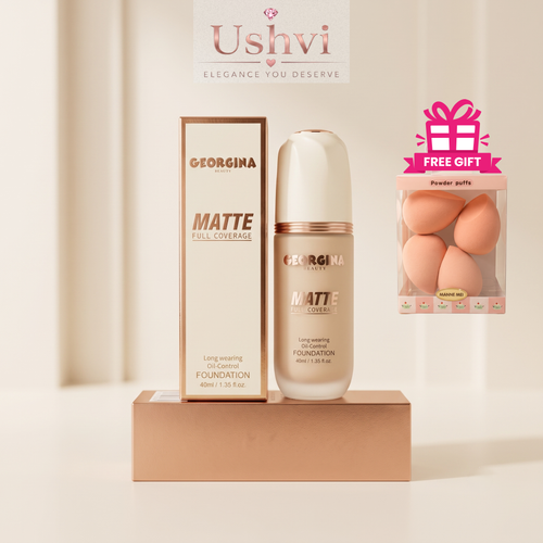 Georgina Mattie Full Coverage Matte Foundation bottle and box displayed on a pedestal, with a pink 'Free Gift' powder puff pack and a Ushvi banner in the background.