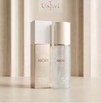 Ushvi RBORY Makeup Setting Spray shown with its beige and white box and the clear spray bottle with a white cap on a light beige surface, with a soft beige curtain background.