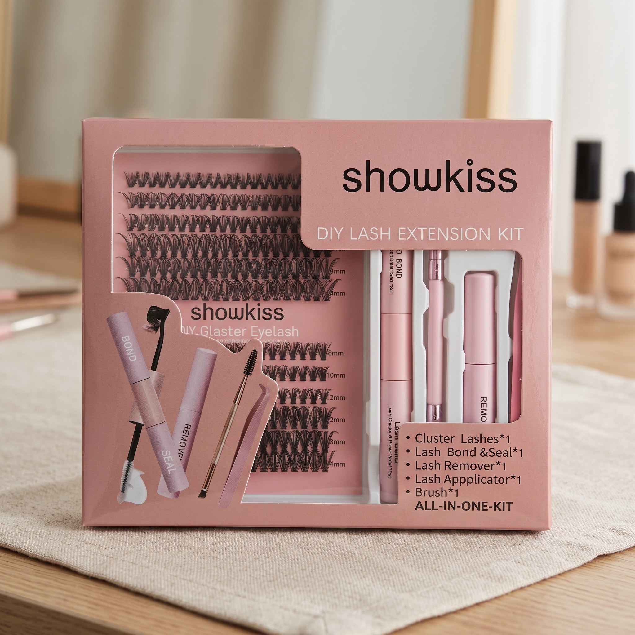 A false eyelash kit by showkiss, containing multiple rows of black false eyelashes on a pink card, a pink brow pencil, a pink mascara tube, and a pink tweezzer, arranged in a white tray on a green artificial grass background.
